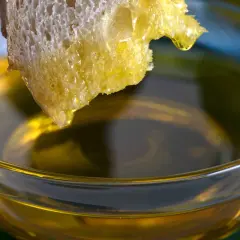 Kawałek chleba zanurzony w oliwie z oliwek w szklanej miseczce.